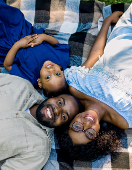 Smiling family laying down on the floor looking up.