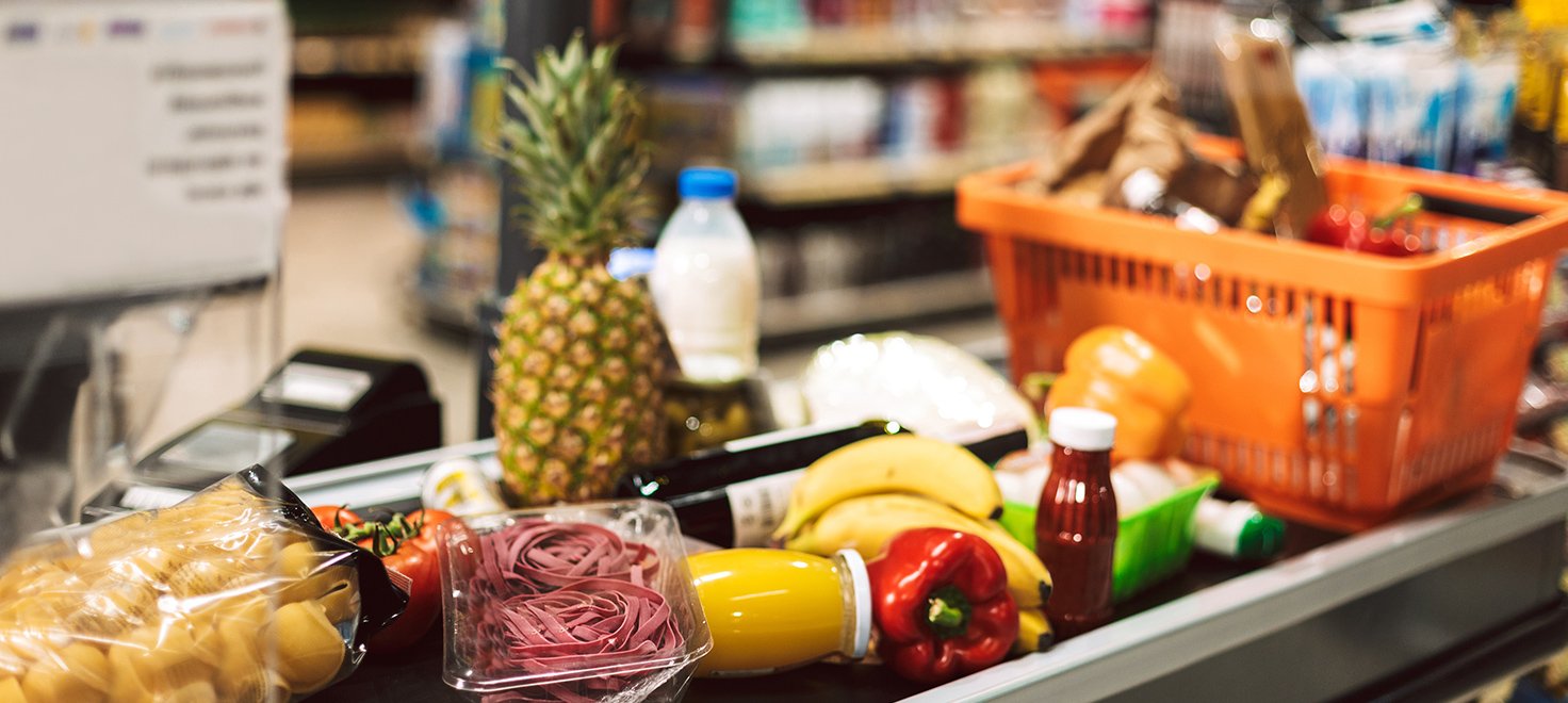 Different food products on a supermarket checkout counter.