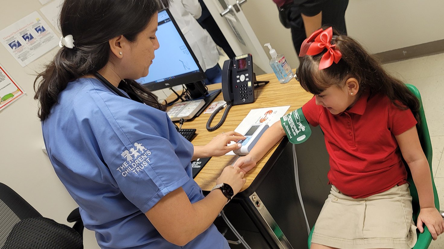School health clinic nurse examines young girl.