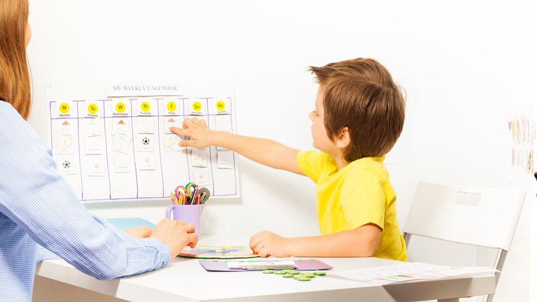 Young boy pointing at a paper calendar glued to a wall